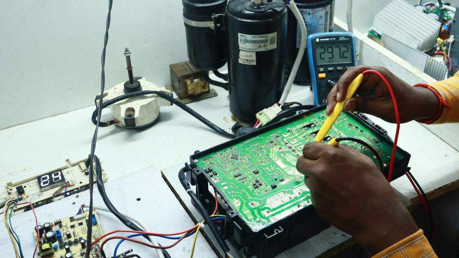 Technician working on AC PCB with tools and equipment, captured in New Delhi workshop.